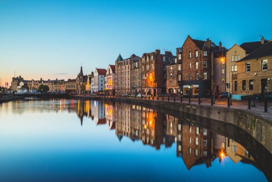 Quais de Leith Shore au crépuscule, bordés de bâtiments en briques et de bateaux amarrés dans l'ancien quartier portuaire d'Édimbourg.