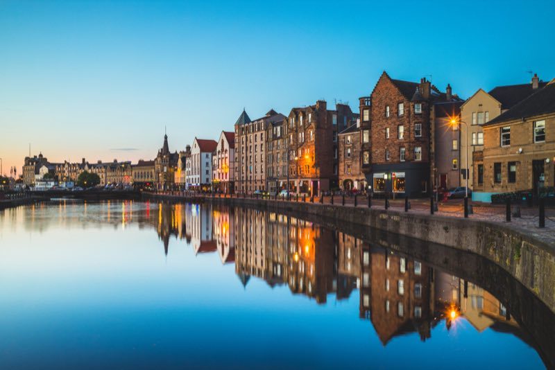 Quais de Leith Shore au crépuscule, bordés de bâtiments en briques et de bateaux amarrés dans l'ancien quartier portuaire d'Édimbourg.