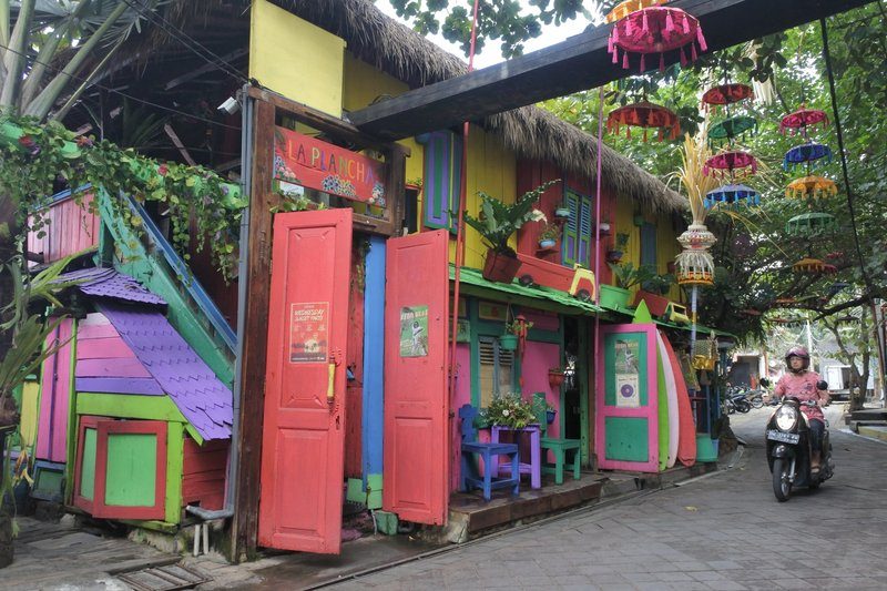 Une rue colorée à Seminyak avec un restaurant animé, idéale pour découvrir l