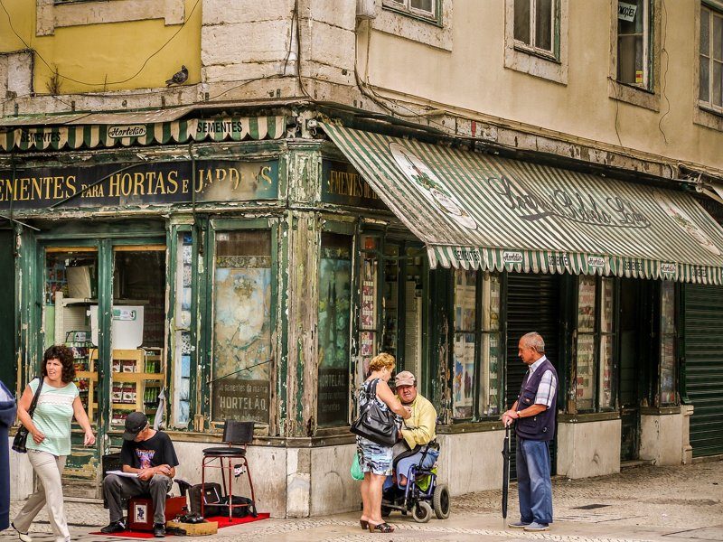 Scène de rue à Lisbonne, Portugal, avec des passants et un vieux magasin.
