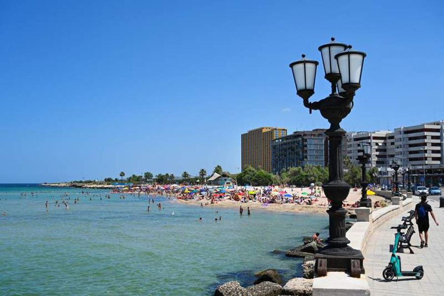Plage de Bari en été, avec ses eaux cristallines et ses parasols multicolores le long du front de mer.