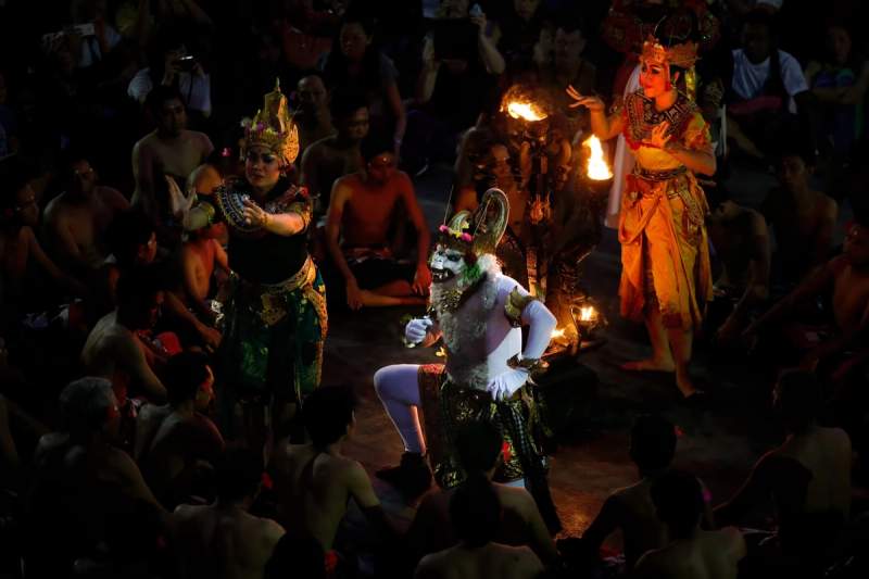 Scène du spectacle de danse Kecak à Uluwatu avec des personnages traditionnels et des torches allumées.