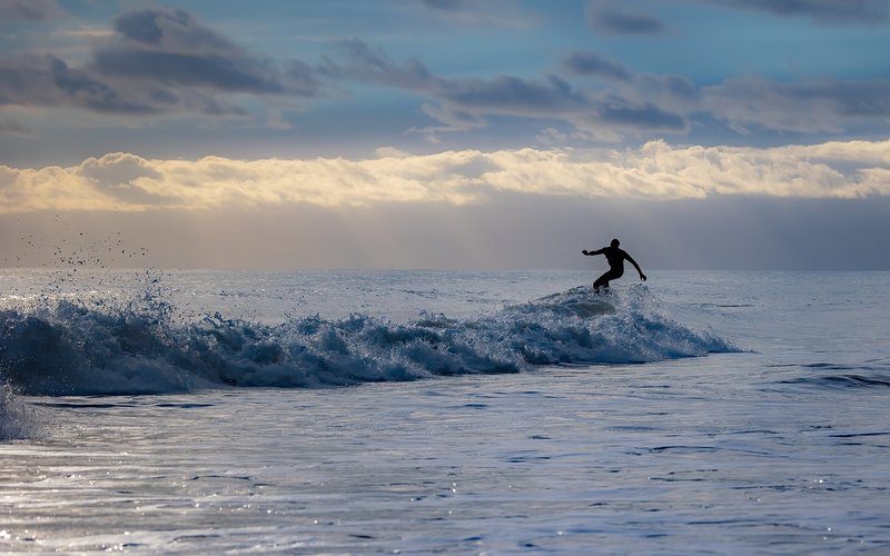 Un surfeur attrapant une vague à Porto, montrant les conditions idéales pour le surf sur les plages de la région.