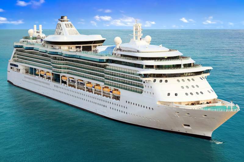 Un grand navire de croisière blanc naviguant sur une mer calme sous un ciel bleu, équipé de nombreux balcons et structures modernes pour accueillir les passagers.