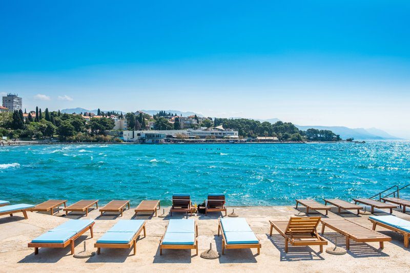Transats alignés sur la plage de Bačvice avec la mer Adriatique scintillante en arrière-plan.