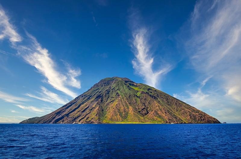 Le volcan Stromboli entouré d’une mer bleue et d’un ciel dégagé.
