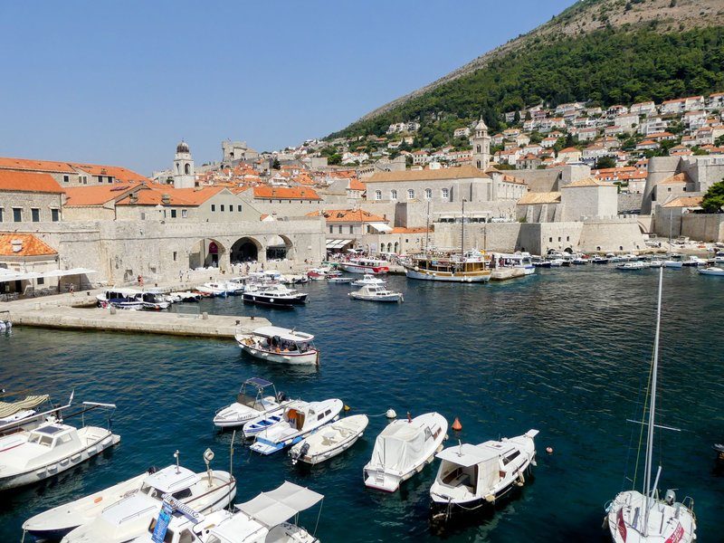 Vue panoramique du vieux port de Dubrovnik avec ses bateaux de plaisance amarrés, les remparts médiévaux et les toits de tuiles oranges de la vieille ville classée UNESCO
