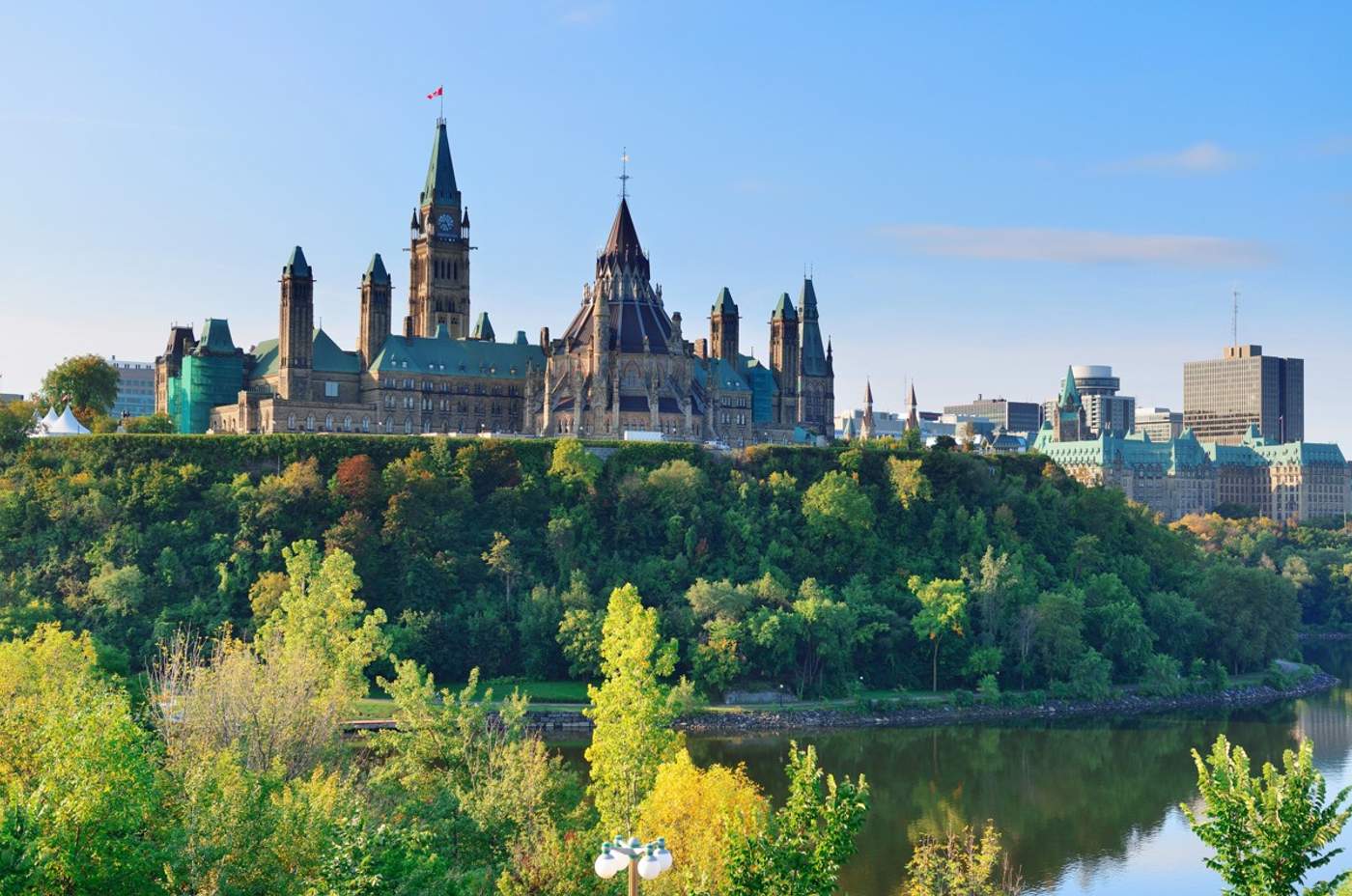 Vue panoramique de la Colline du Parlement à Ottawa, entourée de verdure et surplombant la rivière des Outaouais