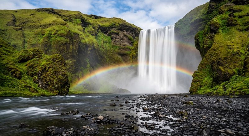 La majestueuse cascade de Skogafoss en Islande entourée de mousse verte sous le soleil d