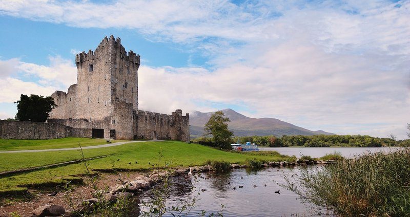 Paysage pittoresque des lacs de Killarney avec un château en arrière-plan.
