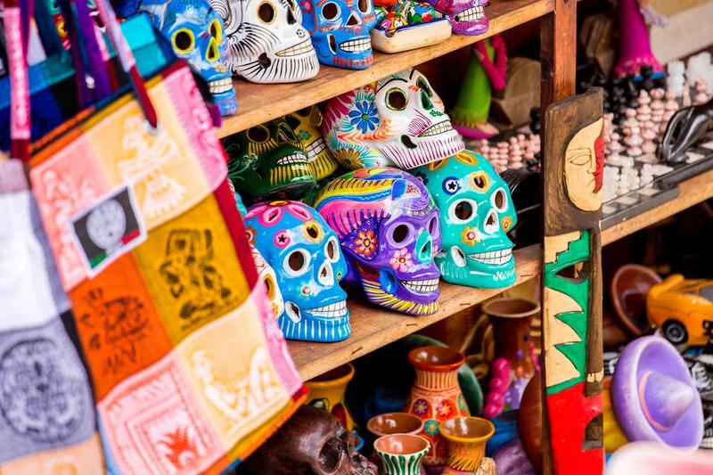 Étagère remplie de crânes mexicains colorés en céramique, décorés de motifs floraux et géométriques, typiques de la fête du Jour des Morts.