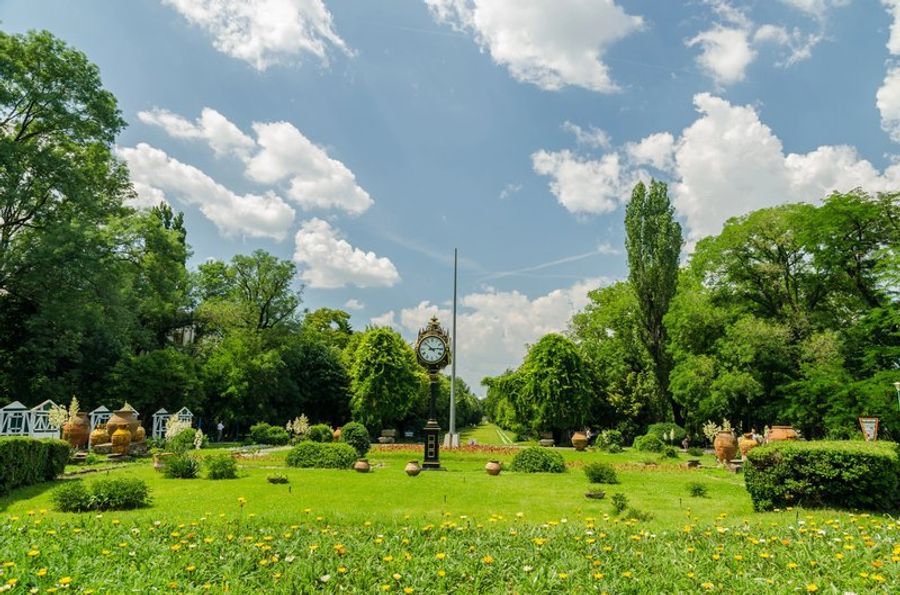 Jardin verdoyant du parc Cișmigiu par une journée ensoleillée, parsemé de fleurs et de sentiers