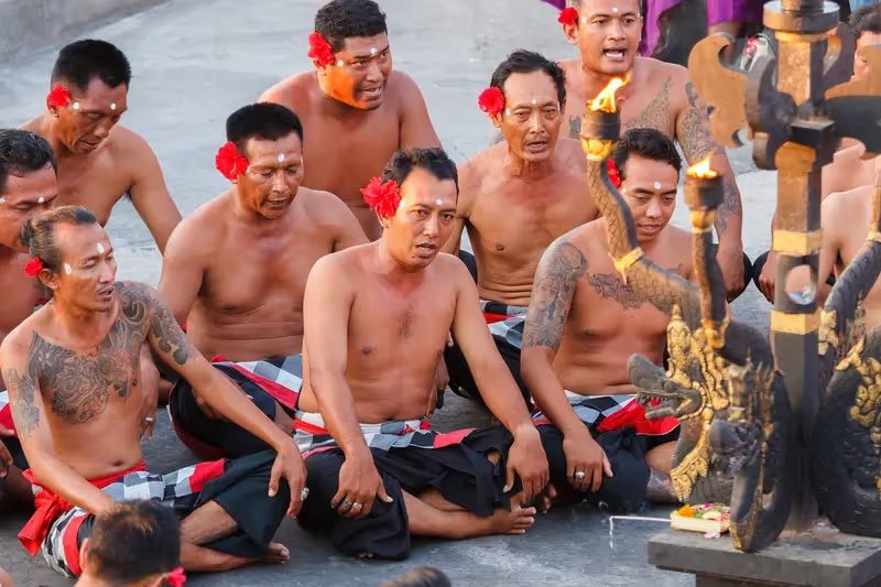 Hommes balinais en tenue traditionnelle participant à une cérémonie culturelle avec des torches enflammées.