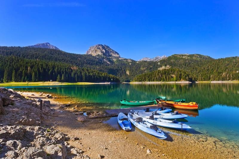 Le lac Noir (Crno Jezero) dans le parc national du Durmitor au Monténégro, avec des barques colorées amarrées sur ses eaux cristallines