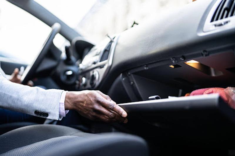Main d'un conducteur ouvrant la boîte à gants de sa voiture sur le tableau de bord.