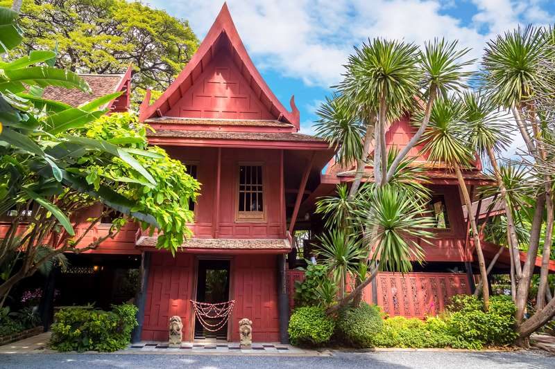 Maison traditionnelle en bois entourée de végétation tropicale.