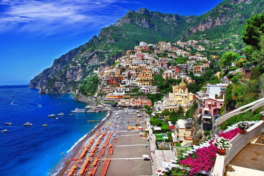 Vue panoramique de la plage colorée de Positano avec ses bâtiments pittoresques accrochés à la falaise.