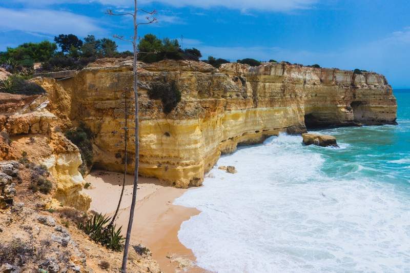 Vue des falaises de Praia da Marinha, Algarve, Portugal, avec une plage de sable et des eaux turquoise.