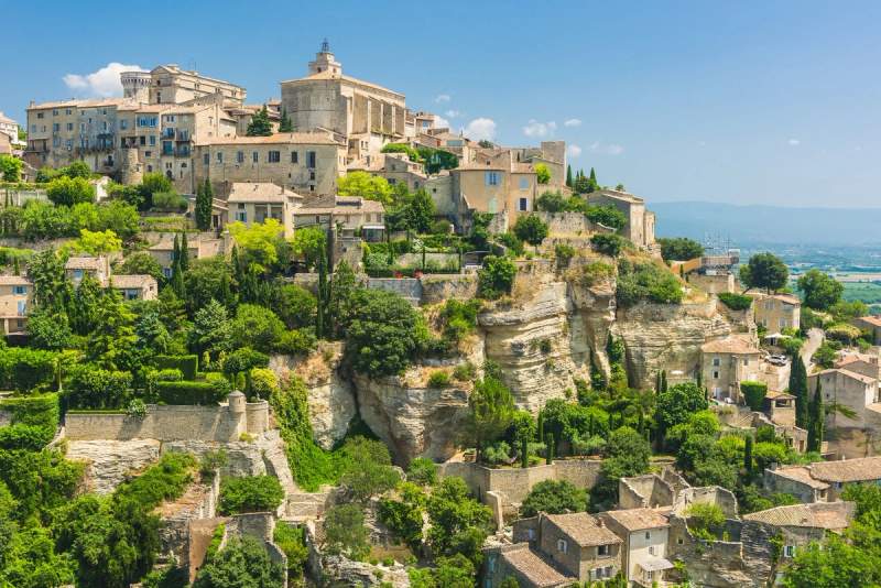 Vue pittoresque du village perché de Gordes, avec ses maisons en pierre et une végétation luxuriante.