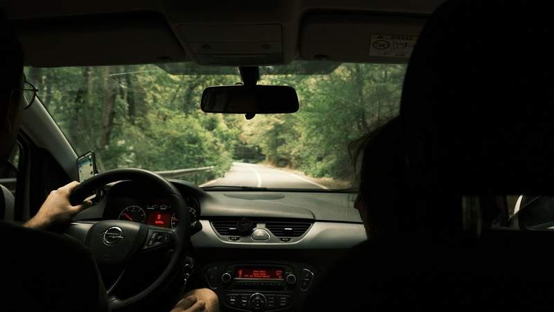Route sinueuse en forêt vue depuis l'intérieur d'une voiture en conduite