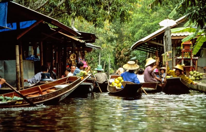 Marché flottant de Damnoen Saduak en Thaïlande, avec des vendeurs sur des bateaux traditionnels.