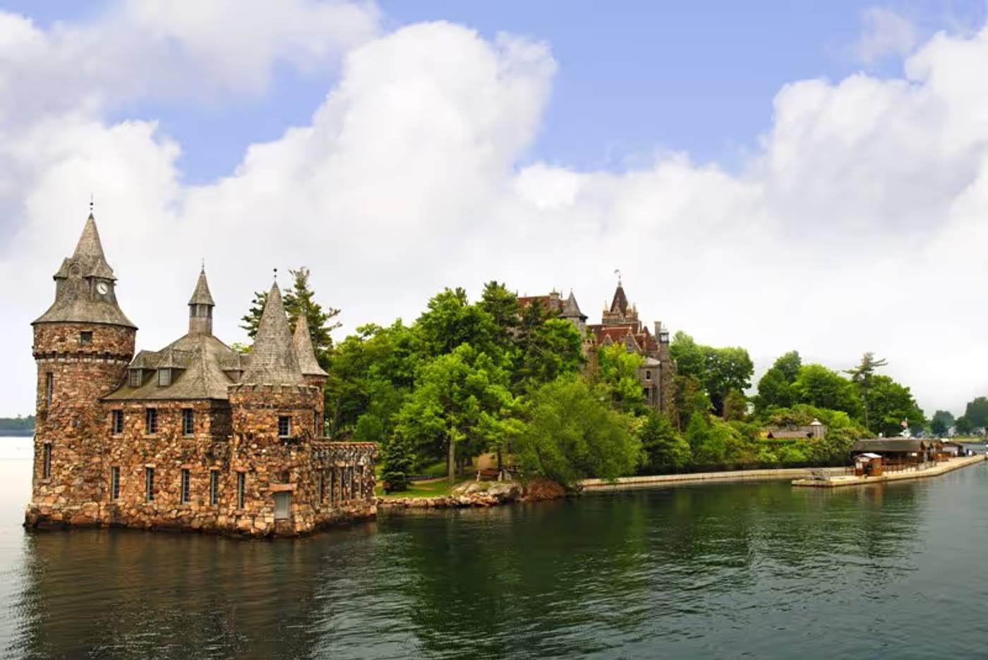 Un château de style médiéval situé sur une petite île entourée d’eau et de verdure.