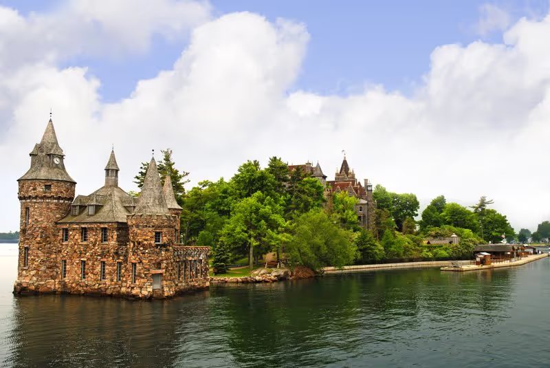 Un château de style médiéval situé sur une petite île entourée d’eau et de verdure.