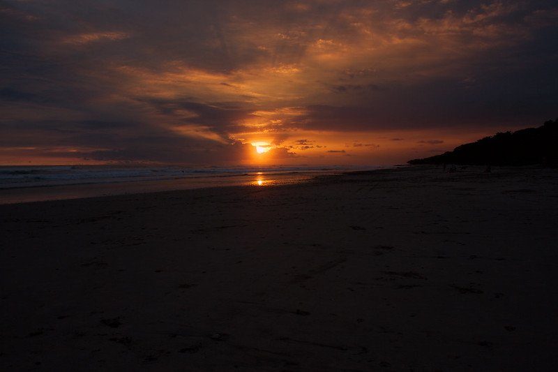 Coucher de soleil sur une plage de sable à Playa Carmen, avec des reflets orange et roses sur l