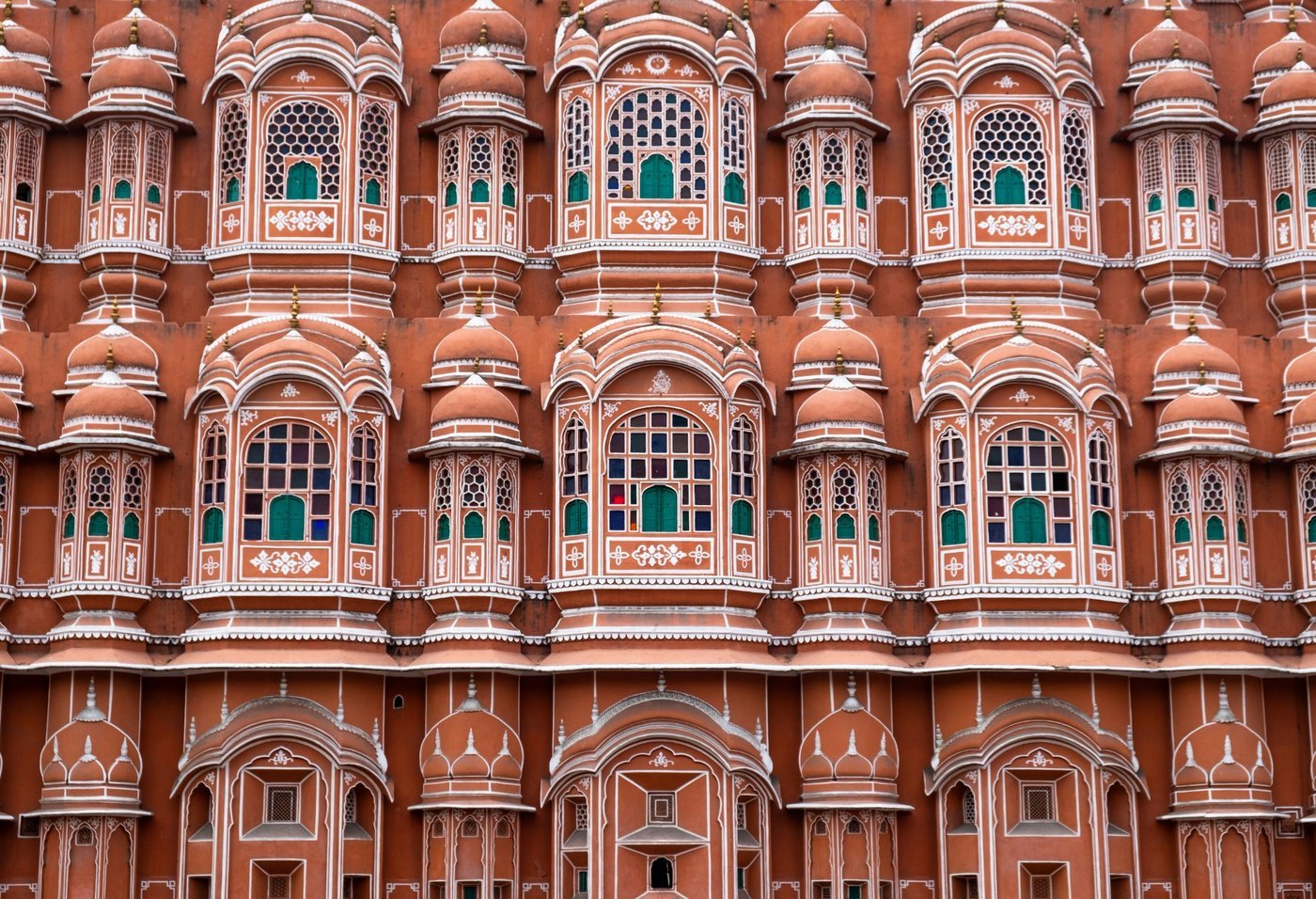 Façade rose ornée du Palais des Vents à Jaipur, avec ses nombreuses fenêtres décorées typiques de l’architecture rajput.