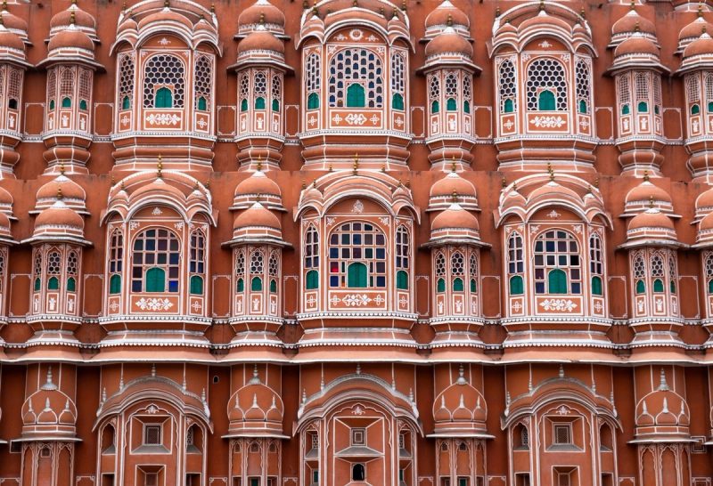 Façade rose ornée du Palais des Vents à Jaipur, avec ses nombreuses fenêtres décorées typiques de l’architecture rajput.