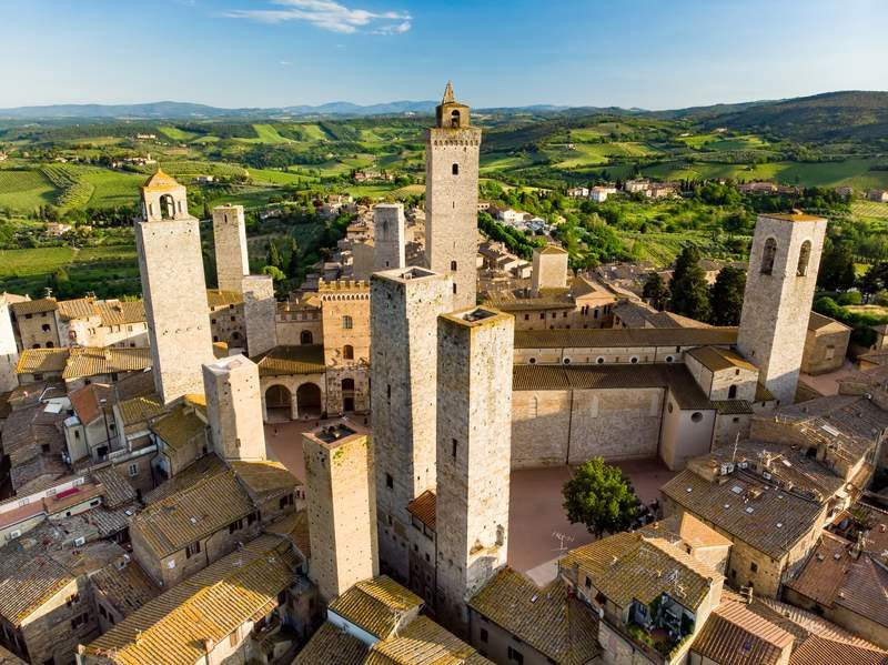 Vue aérienne des tours médiévales de San Gimignano, dont la célèbre Torre Grossa, entourée de la campagne toscane.