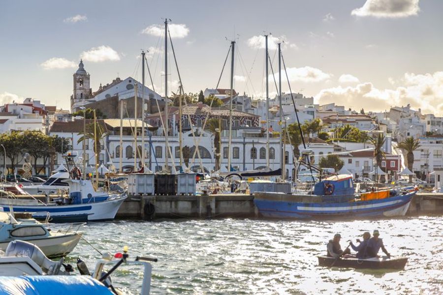 La marina de Lagos, avec des bateaux de pêche et des voiliers amarrés, sous un ciel ensoleillé.