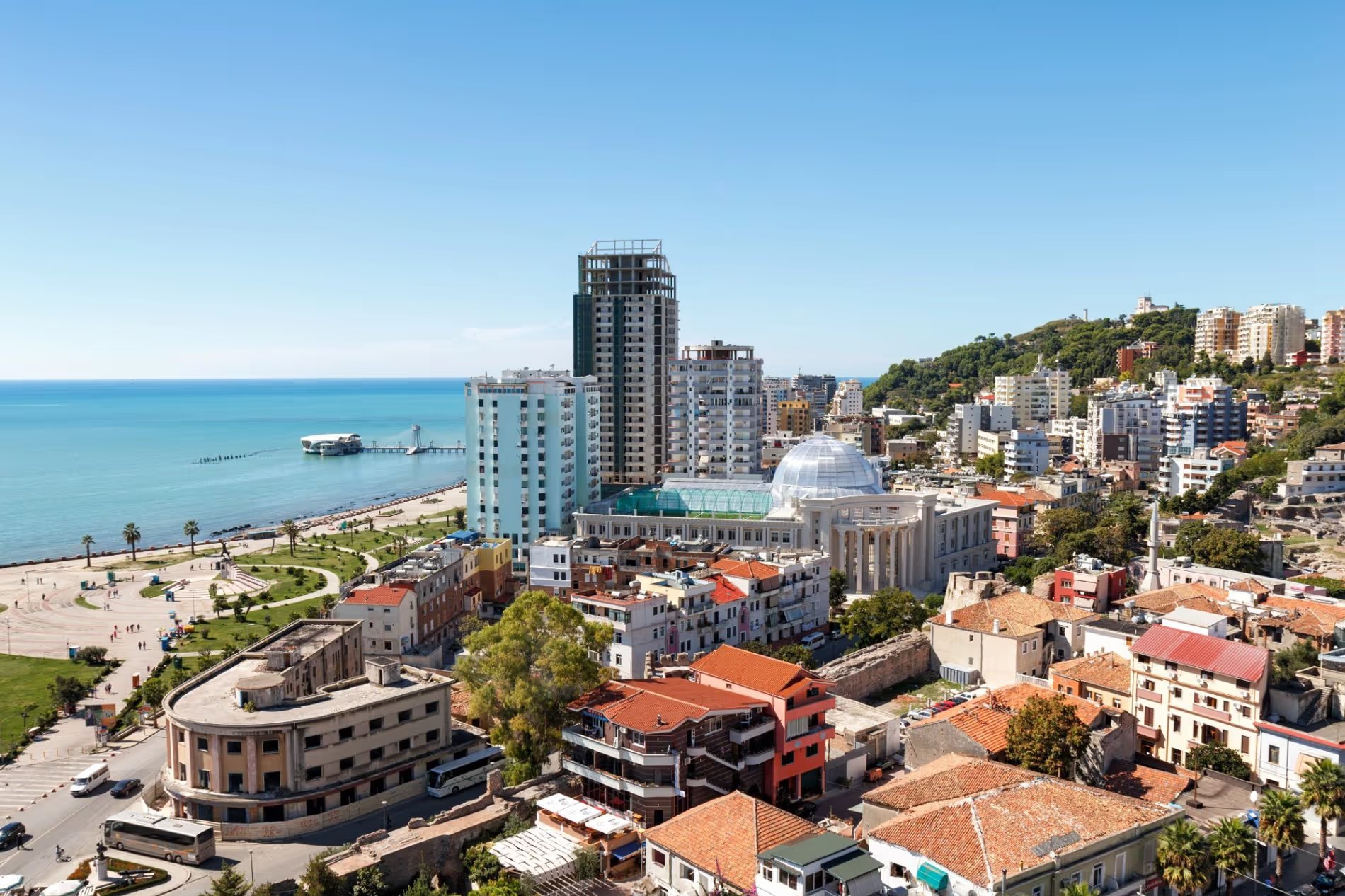 Vue panoramique de la ville de Durrës en Albanie, avec des bâtiments modernes, une promenade en bord de mer, et la mer Adriatique en arrière-plan.