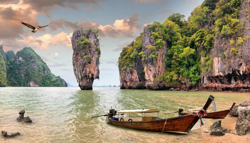 Paysage emblématique de la Baie de Phang Nga avec ses formations rocheuses spectaculaires et des bateaux traditionnels.