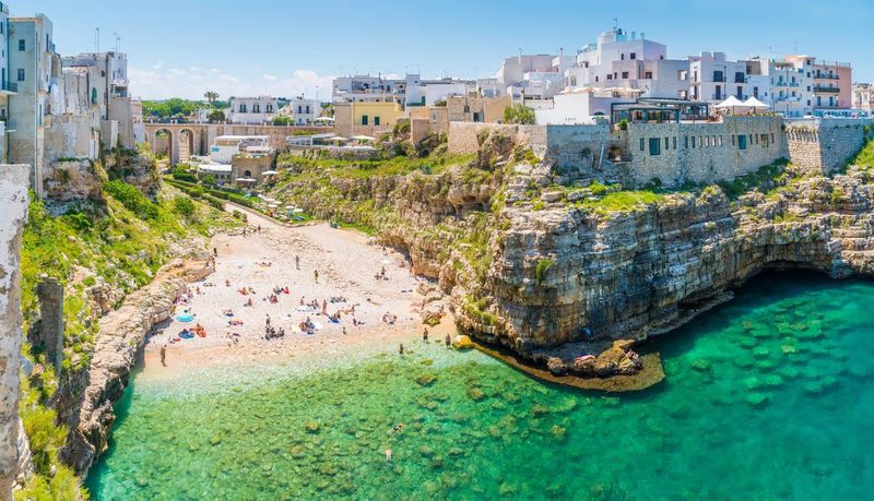 Plage de galets et eaux turquoise entourées de falaises à Polignano a Mare, dans les Pouilles, Italie.