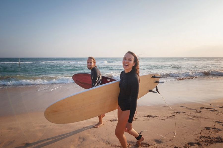 Deux surfeurs souriants avec leurs planches sur la plage de Dewata près de Galle