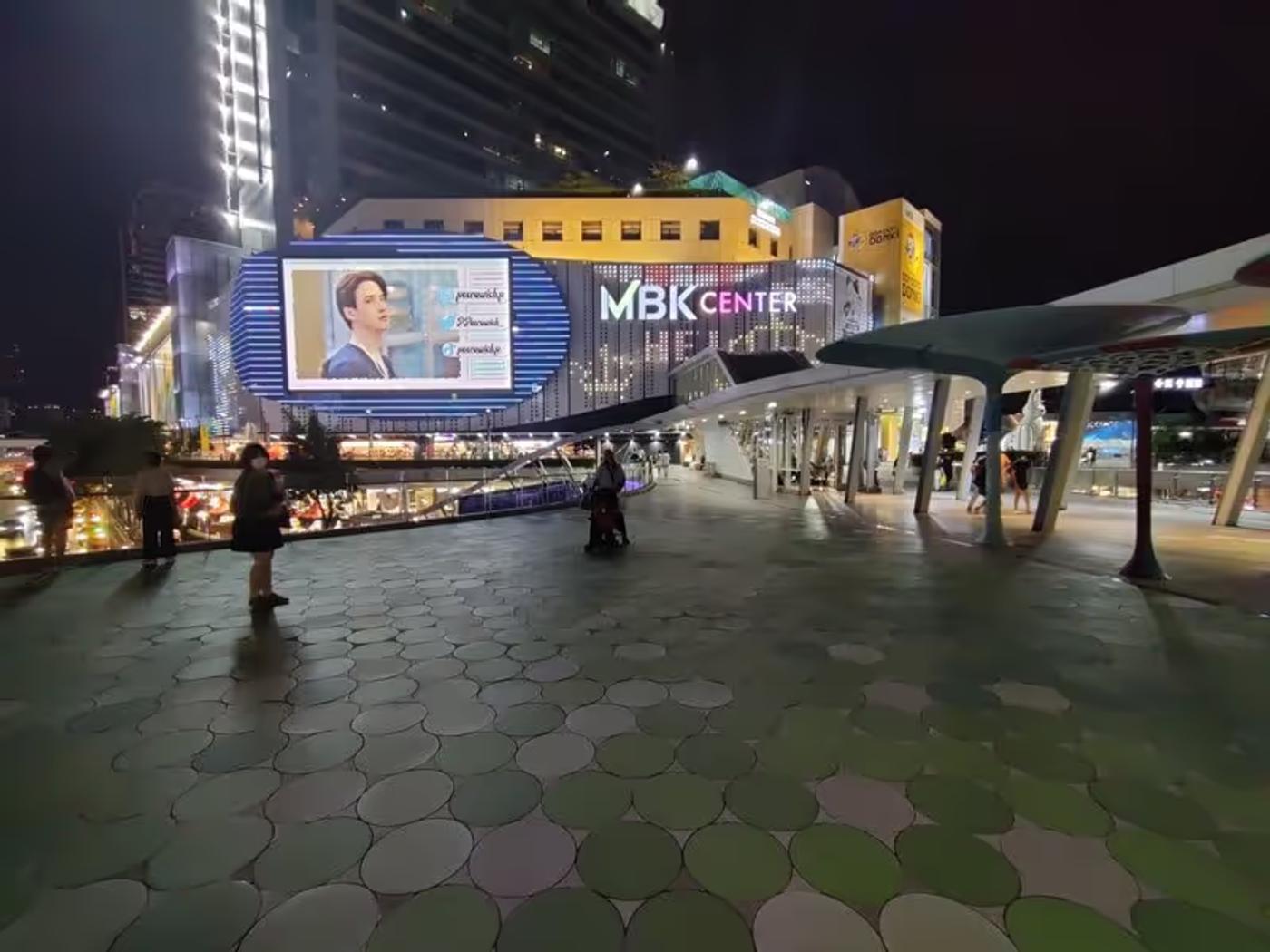 Vue nocturne du centre commercial MBK Center à Bangkok, illuminé par ses enseignes colorées.