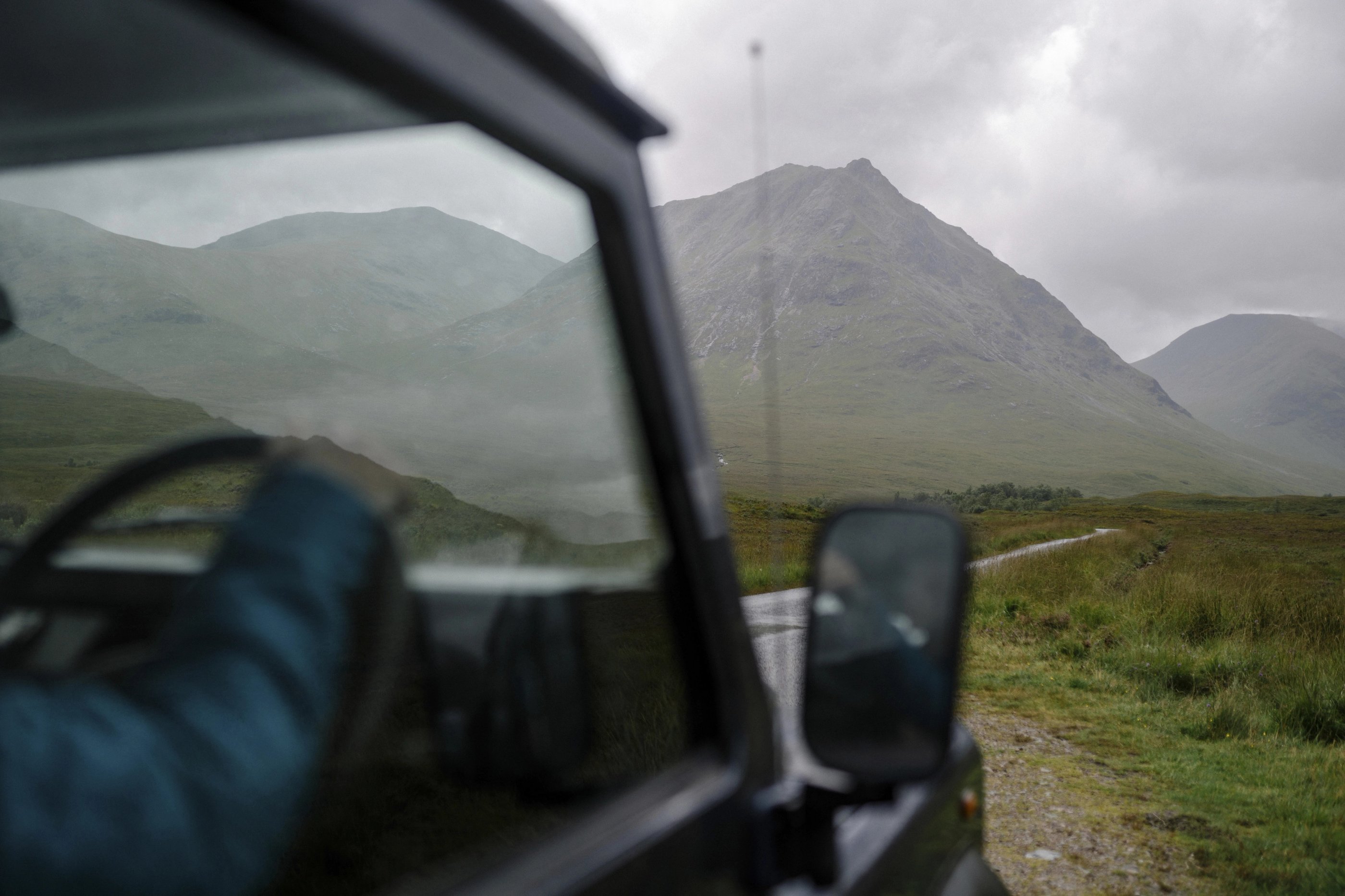 Vue depuis une voiture sur une route des Highlands en Écosse, sous un ciel couvert