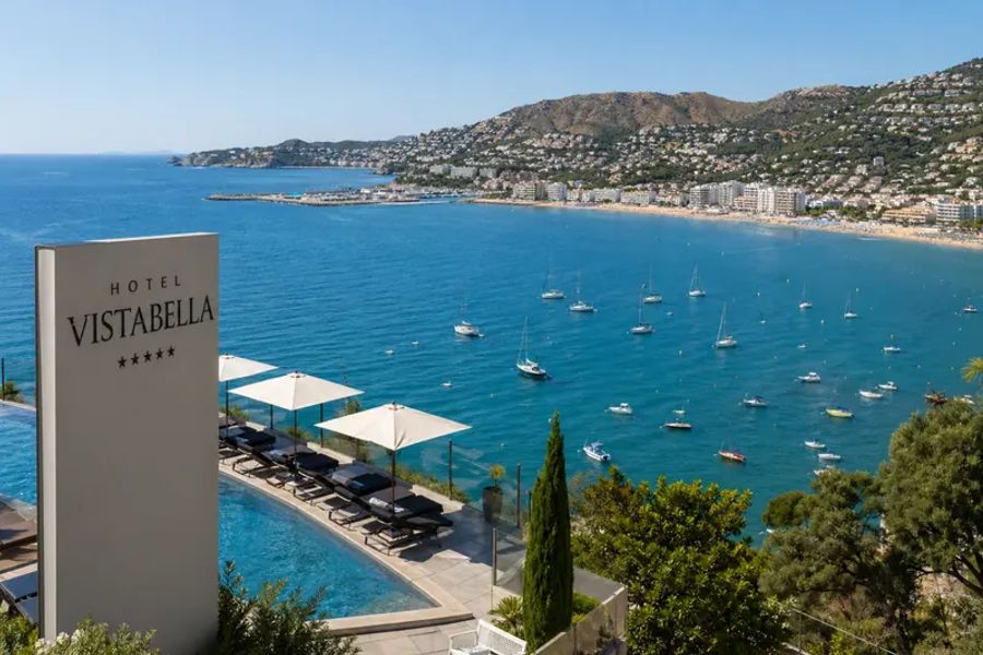 Vue panoramique depuis l’Hotel Vistabella à Roses sur la Costa Brava avec piscine, mer Méditerranée et bateaux dans la baie.