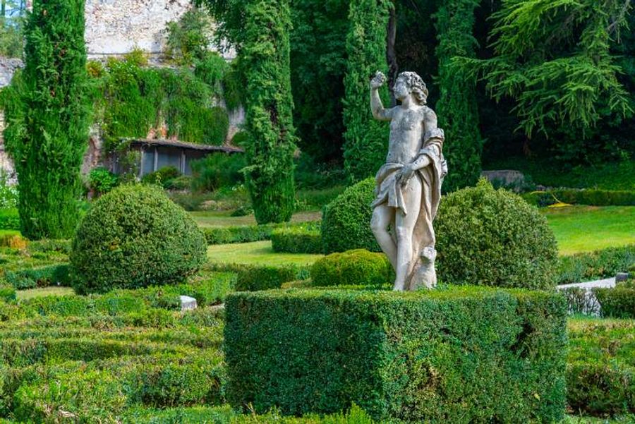 Statue dans les jardins Giusti, entourée de haies parfaitement taillées et d’arbres majestueux.