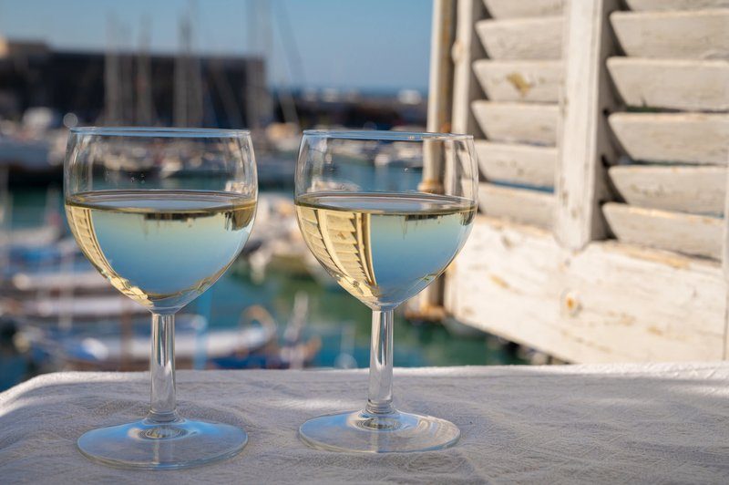 Deux verres de vin blanc local avec le port de Cassis en arrière-plan.