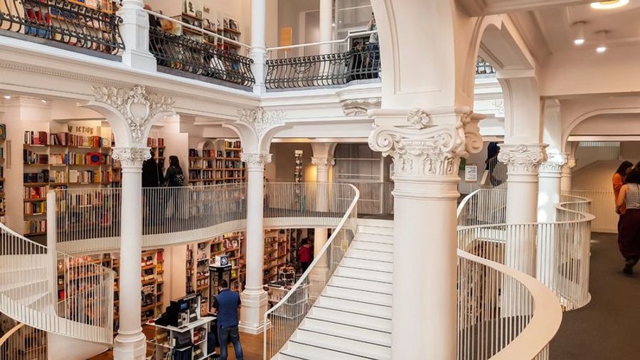 Intérieur lumineux et élégant de la librairie Cărturești Carusel, avec des balcons et des étagères en colimaçon dans un bâtiment historique.