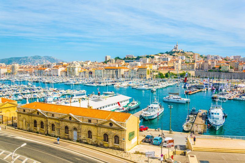 Vue sur le Vieux-Port de Marseille avec ses bateaux et Notre-Dame de la Garde en arrière-plan.