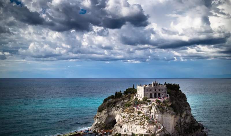 Vue panoramique de Santa Maria dell'Isola à Tropea, Italie, avec la mer et un ciel nuageux en arrière-plan.
