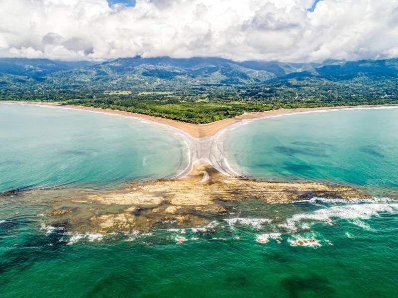 Vue aérienne spectaculaire de la formation naturelle en forme de queue de baleine sur la plage d'Uvita, Costa Rica, entourée par l'océan turquoise et la forêt tropicale luxuriante.