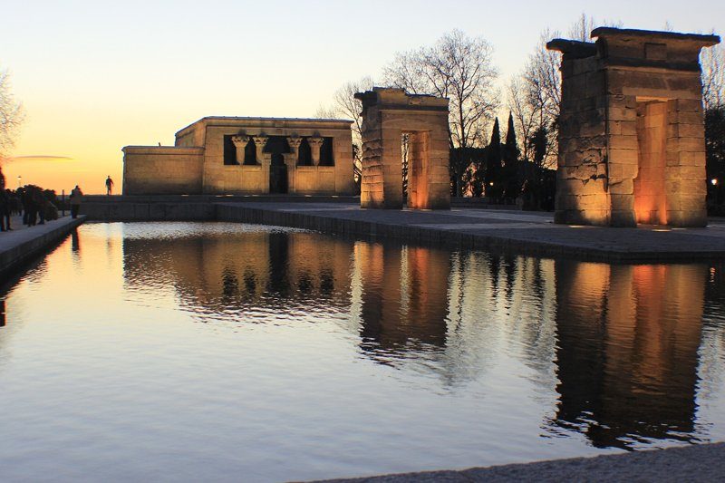 Temple égyptien au coucher du soleil avec reflet dans le bassin.