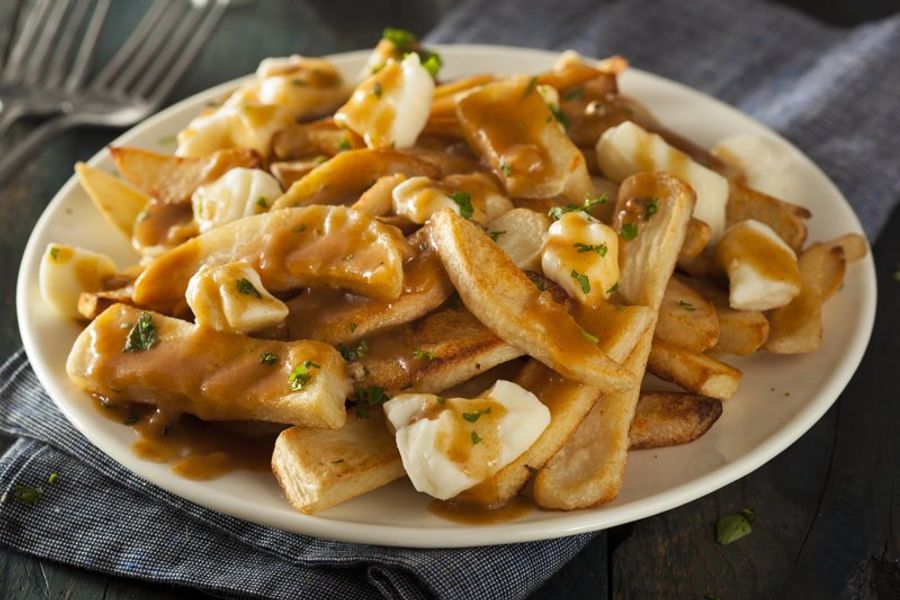Assiette de poutine traditionnelle avec frites croustillantes, fromage en grains et sauce brune.