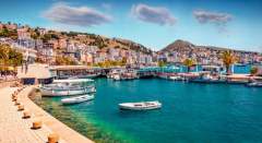 Vue sur le port de Saranda, en Albanie, avec ses bateaux amarrés et la ville en arrière-plan, entourée de collines et de la mer Ionienne.