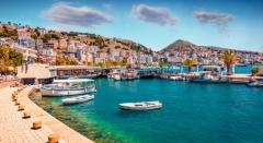 Vue sur le port de Saranda, en Albanie, avec ses bateaux amarrés et la ville en arrière-plan, entourée de collines et de la mer Ionienne.