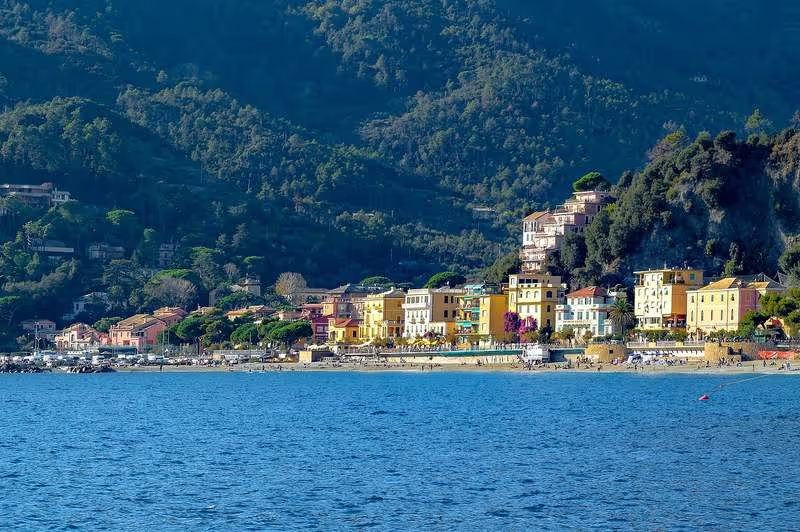 Vue panoramique sur Monterosso al Mare, avec ses bâtiments colorés au bord de la mer et des collines verdoyantes en arrière-plan.